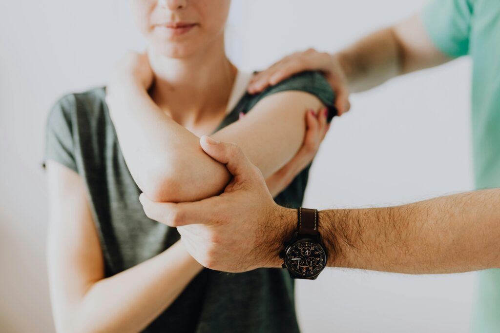 Crop unrecognizable chiropractor examining arm joint of female patient